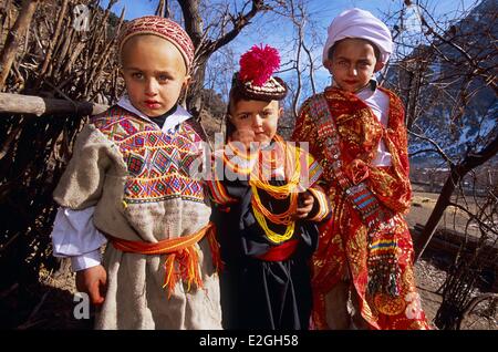 Vallées Kalash Khyber Pakhtunkhwa au Pakistan Bumburet valley petit 4 ans, fille, couverts de sa première robe et chapeau entouré par deux jeunes garçons de 7 ans habillé en berger et guerrier Kalash après leurs rituels initiatiques de mais Sambiak et Tchelik S Banque D'Images