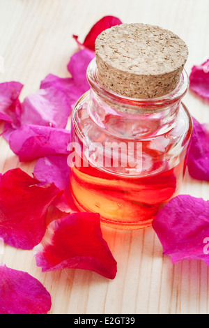 Huile essentielle dans le flacon en verre et pétales de rose Banque D'Images