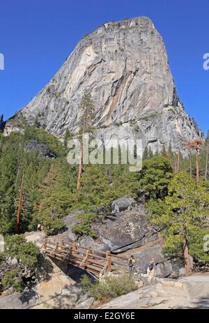 États-unis Californie Sierra Nevada Yosemite National Park classé au Patrimoine Mondial par l'UNESCO La Vallée Yosemite les randonneurs à pied pont traversant la rivière Merced sur le sentier à Nevada Fall Liberty Cap dôme de granit en arrière-plan Banque D'Images