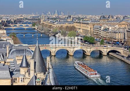 France Paris bords de Seine inscrite au Patrimoine Mondial de l'UNESCO vu l'Ile de la Cité pont neuf et un bateau-mouche Bateau de tourisme du Louvre et quartier d'affaires de la Défense en arrière-plan Banque D'Images