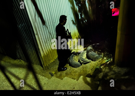 Un policier de l'unité d'urgence spécial chasse soi-disant membres d'un gang dans la nuit à San Salvador, El Salvador. Banque D'Images