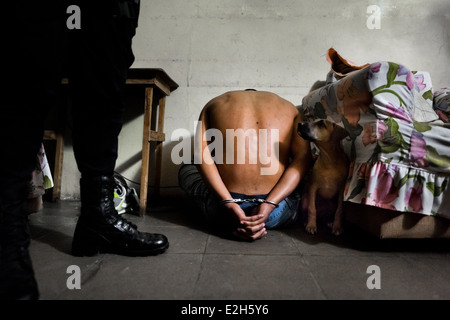 Un présumé membre d'un gang est vu menotté par l'unité spéciale anti-gang lors d'un raid de nuit à San Salvador, El Salvador. Banque D'Images