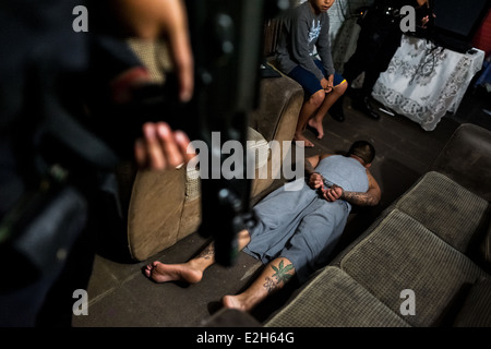 Un membre de gang présumé se trouve sur le sol lors d'un raid nocturne de Soyapango, un quartier d'un gang à San Salvador, El Salvador. Banque D'Images