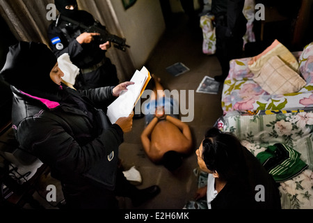 Un membre de gang présumé se trouve sur le sol lors d'un raid nocturne de Soyapango, un quartier d'un gang à San Salvador, El Salvador. Banque D'Images