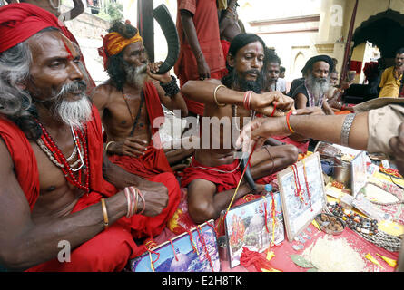 Guwahati, Inde. 19 Juin, 2014. Un saint homme cravates un thread sur la main d'un dévot dans les locaux de temple Kamakhya en avant de l'Ambubasi annuel festival qui commencera à partir de dimanche à Guwahati, Inde, le 19 juin 2014. Credit : Stringer/Xinhua/Alamy Live News Banque D'Images