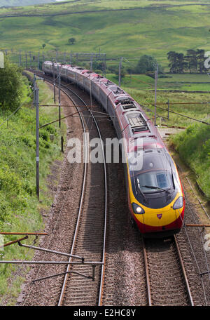 Shap, Westmorland, UK 19 Juin, 2014. La ligne vierge de la côte ouest de Franchise renouvelé. Voyager et Pendolino Virgin Trains de voyageurs Voyager à Shap, Cumbria, Royaume-Uni. Virgin Trains et le ministère des Transports ont signé un nouveau pacte garantissant une amélioration importante pour les voyageurs et les contribuables. La nouvelle franchise de la côte ouest se déroulera jusqu'en mars 20171 et verront des améliorations significatives pour les clients avec l'introduction du libre-superfast Connexion Wi-Fi au réseau local, plus de sièges et de nouveaux services. Banque D'Images