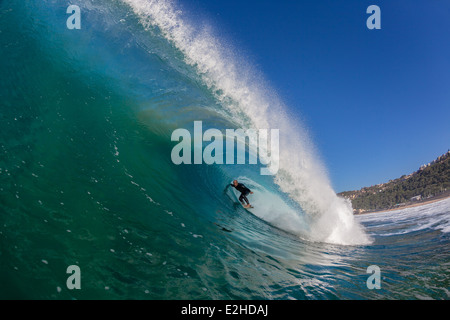Surf surfer dans de grandes promenades en tubes creux des vagues s'écraser d'une photo d'action de l'eau. Banque D'Images