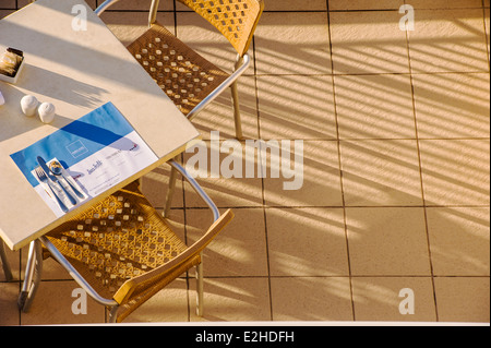 Un cafe table dressée pour le petit déjeuner, tôt le matin, la lumière du soleil. Banque D'Images