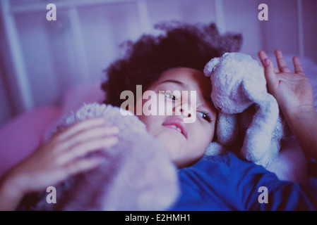 Petite fille couchée avec des jouets en peluche Banque D'Images