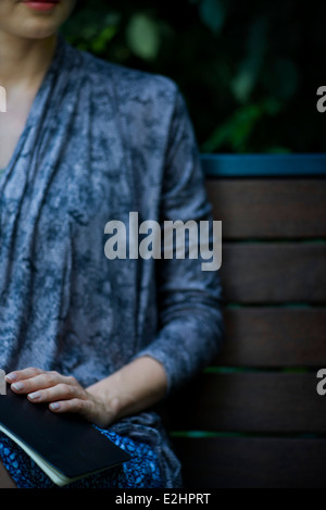 Femme assise sur un banc de travail avec livre sur tour, cropped Banque D'Images