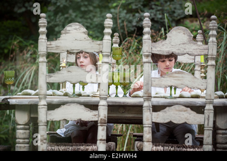 Les enfants assis à table de salle à manger en plein air Banque D'Images