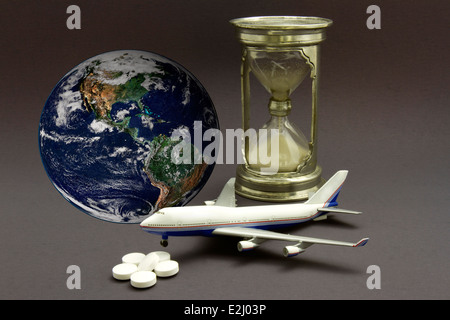 Avion miniature avec un sablier, pilules et globe pour représenter le concept du décalage horaire Banque D'Images