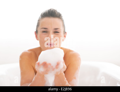 Portrait of happy young woman playing avec mousse dans la baignoire Banque D'Images