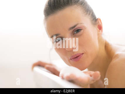 Portrait of happy young woman playing avec mousse dans la baignoire Banque D'Images