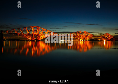 Scotland's Forth Rail Bridge allumé à une nuit de printemps avec une mer calme. Banque D'Images