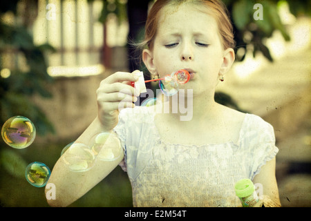 Style rétro photo de jeune fille soufflant des bulles de savon Banque D'Images