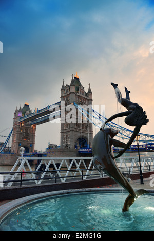 Le Tower Bridge et la statue d'une jeune fille jouant avec dauphin en St Katharine Docks de Londres. Banque D'Images