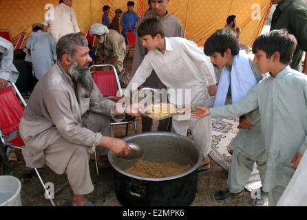 Bannu. 20 Juin, 2014. Un homme distribue le riz parmi les civils, fuyant le Waziristan du Nord, région tribale pour Bannu le 20 juin 2014. Armée du Pakistan a dit vendredi que 200 000 personnes ont quitté maisons dans le Waziristan du Nord, région tribale comme les forces de sécurité ont poursuivi l'opération contre des militants locaux et étrangers. Credit : Ahmad Sidique/Xinhua/Alamy Live News Banque D'Images