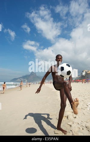 RIO DE JANEIRO, Brésil - Mars 2011 : Jeune homme brésilien botter un football sur la plage d'Ipanema dans un jeu de keepy uppy altinho. Banque D'Images