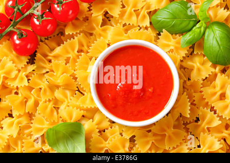 Noeud papillon non cuit des pâtes et de la purée de tomates Banque D'Images