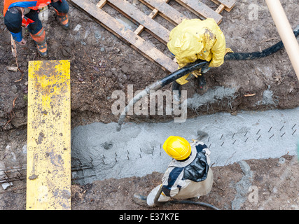 Les travailleurs de la construction pour le béton dans un fossé. Temps de pluie. Vue à vol d'oiseau. Banque D'Images