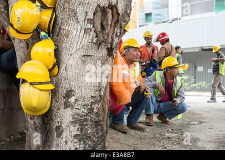 Les travailleurs migrants de prendre une pause de leur travail sur un chantier de construction dans le centre de Kuala Lumpur, Malaisie Banque D'Images