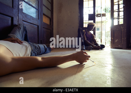 African American man et caucasienne dans guy (USA), l'injection de l'héroïne avec la seringue et couché sur la chaussée Banque D'Images