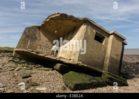 WW2-casemate béton ère défense structure se trouve sur la plage après l'érosion côtière au point des gardes, à l'île de Sheppey, Kent. Banque D'Images