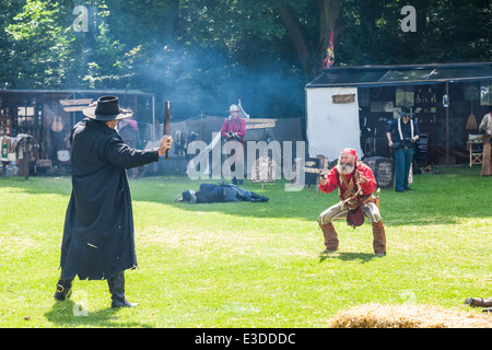 Poireau, Staffordshire, Angleterre. 22 juin 2014, un week-end country et western. Deux cowboys tirer leurs armes les uns sur les autres Banque D'Images