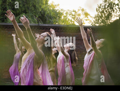 Old Westbury, New York, USA. 21 Juin, 2014. Vu à travers les feuilles des arbres, Lori Belilove & La Compagnie de danse Isadora Duncan effectuer la danse moderne, levant les bras élevés vers le ciel, pendant la nuit au milieu de l'événement au Long Island Gold Coast estate de Old Westbury Gardens le premier jour de l'été, le solstice d'été. © Ann Parry/ZUMA/ZUMAPRESS.com/Alamy fil Live News Banque D'Images