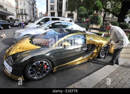 Les passants s'arrêter pour vérifier deux voitures flashy garé à l'extérieur de la face de l'Hôtel Dorchester. Une Lamborghini Aventador violet et jaune et or Bugatti Veyron. En vedette : Bugatti Veyron Où : London, Royaume-Uni Quand : 20 Oct 2013 Banque D'Images