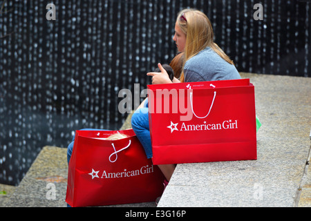 Fille assise avec American Girl Doll holding shopping bags, Chicago Banque D'Images