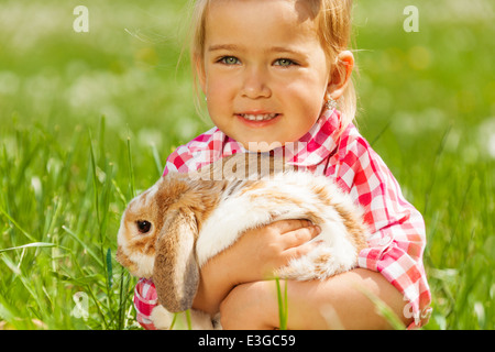 Cute girl de câliner lapin dans green field Banque D'Images