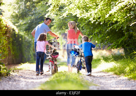 Poussant la famille de vélos le long de la voie de Pays Banque D'Images