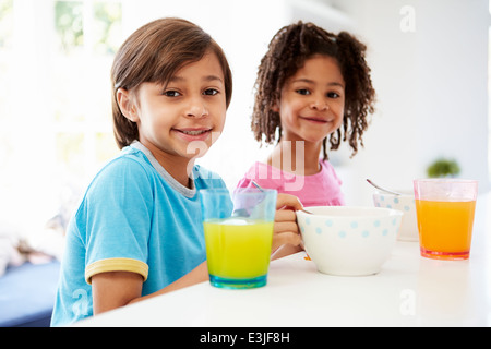 Deux enfants ayant le petit déjeuner dans la cuisine ensemble Banque D'Images
