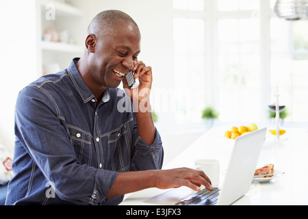 Man et parlant au téléphone dans la cuisine à la maison Banque D'Images