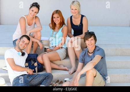 Les élèves assis sur les escaliers de l'école smiling college friends l'heure d'été Banque D'Images