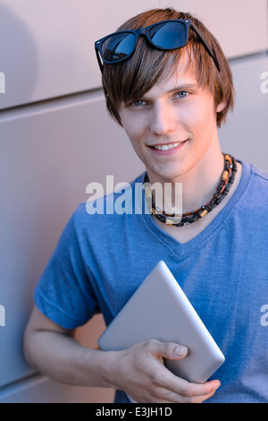 Happy student boy with tablet looking at camera contre mur Banque D'Images