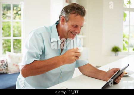 Middle aged Man Using Digital Tablet pendant le petit-déjeuner Banque D'Images