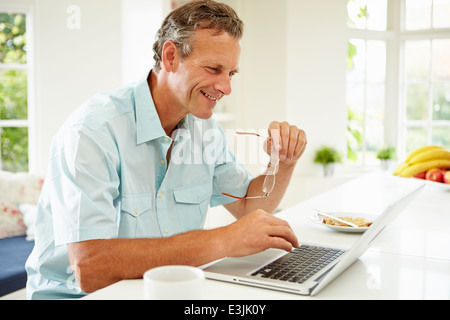 Middle aged Man Using Laptop pendant le petit-déjeuner Banque D'Images