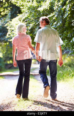 Vue arrière du couple d'âge moyen marcher le long chemin de campagne Banque D'Images