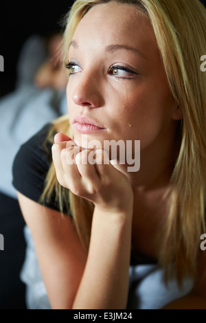 Triste Teenage Girl Sitting dans la chambre tout en petit ami Sleeps Banque D'Images