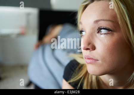 Triste Teenage Girl Sitting dans la chambre tout en petit ami Sleeps Banque D'Images