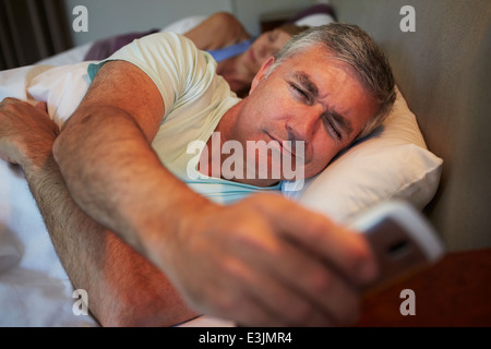 Couple In Bed avec Mari souffrant d'insomnie Banque D'Images