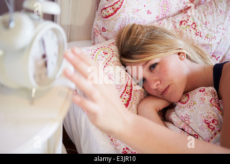 Woman Waking Up In Bed et la mise hors tension de réveil Banque D'Images