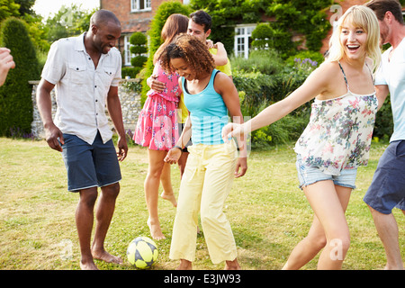 Groupe d'amis à jouer au football dans le jardin Banque D'Images