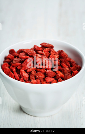 Bol blanc avec les baies de goji sur la table Banque D'Images