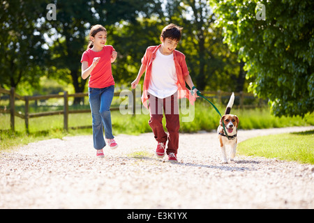 Les enfants hispaniques en tenant pour chien marche dans la campagne Banque D'Images