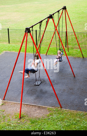 Mère et fille sur balançoires dans park Banque D'Images