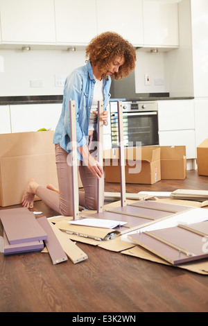 Woman Putting Ensemble mobilier d'auto assemblage in New Home Banque D'Images